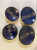 Top view showing all four navy soapstone plates in two sizes with carved bands