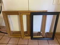 Front view of three empty frames leaning against cabinet