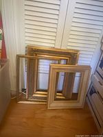 Three stacked gold and cream frames on floor