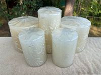 Five Kapula white-on-white hand-painted pillar candles, three large at back, two medium at front
