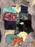 Pile of assorted women's clothing pieces folded on bed