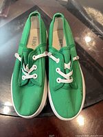 Top view showing green canvas sneakers with white soles and elastic laces