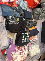 Overview of folded clothing showing denim, graphics and fleece items