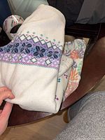 White fleece sweater with purple pattern and floral pants on table