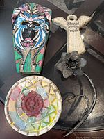 Group image showing wooden painted plaque, ceramic angel plaque, mosaic dish and metal flower