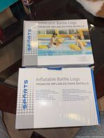 Both sealed Inflatable Battle Logs boxes on table, front panel visible