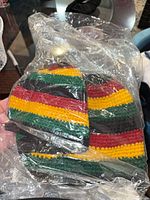 Two striped crocheted beanie hats in clear plastic bag