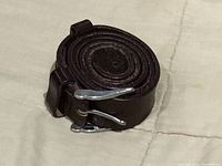 Rolled brown leather belt showing buckle end