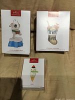 Front view of three Hallmark Keepsake ornament boxes showing titles and artwork