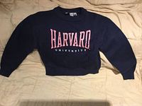 Front view of navy Harvard University sweater laid flat