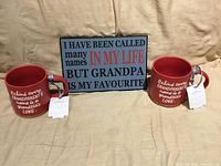 Front view of two mugs and plaque showing designs and condition