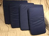 Four navy blue rectangular and square patio cushions displayed on beige surface