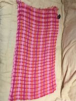 Full view of folded pink/orange plaid silk scarf showing pattern and size perspective