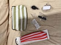 Gold striped clutch purse with included accessory packets and red striped headband laid out