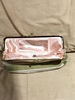 Interior of striped clutch purse showing pink satin lining, built-in mirror and clear sleeve
