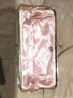 Clutch interior showing pink satin lining and gold frame