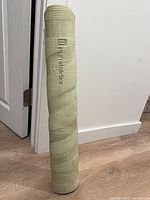 Rolled light green PurAthletics yoga mat standing upright