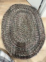 Full view of the small oval braided rug on wooden floor