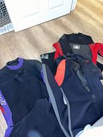 Three wetsuits laid out showing different color schemes