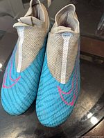 Top view of both cleats showing blue forefoot, pink Swoosh outlines, ghost lace cover