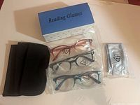 Three sealed reading glasses, pouch, cloth, box overview