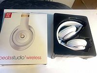 Headphones folded in black plastic tray beside retail box front view