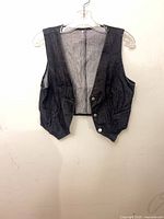 Front view of dark wash denim vest on hanger showing overall design and buttons
