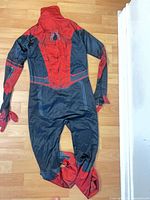 Full view of front side of red and black Spider-Man jumpsuit laid flat on floor
