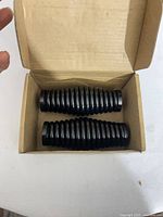 Open box showing two black ribbed cylindrical parts