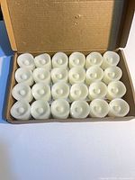 Open box showing 24 white LED votive candles arranged in rows