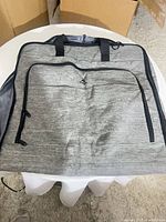 Front of garment bag showing exterior color, front zip pocket, handles