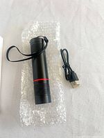 Flashlight with lanyard and USB cable on bubble wrap