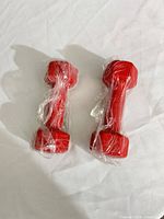 Two red hex dumbbells wrapped in plastic, top view