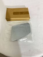 Front of mirror glass in plastic bag beside brown box