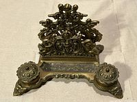front view showing ornate brass backplate, pen tray and both covered inkwells