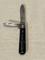 Black-handled twin-blade folding pocket cutter open showing both blades