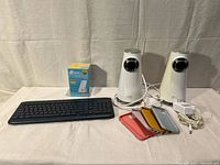 Group shot showing keyboard, TP-Link box, two Altec Lansing speakers, five iPhone cases, power adapter