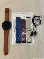 Smartwatch, three sport straps in package, charging cable visible