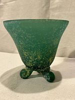 Front view showing speckled green glass dish with three curled feet