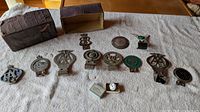 Overall view of twelve automobile hood ornaments and badges with storage box