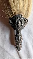 Close-up of ornate silver-plated handle and bristles of crumb brush