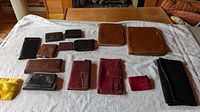 All fifteen wallets, coin purses and card cases laid out flat on a cloth for overview