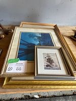 Stack of framed prints showing Parrish print and small tall-ship print