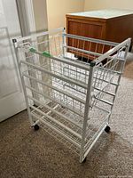 Front view of white metal rolling cart showing baskets and casters