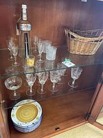 Cabinet view showing plates, stemware, bottle, basket