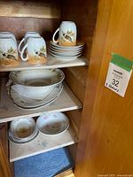 Cabinet shelves showing entire lot: mugs, plates, serving bowls, soup bowls