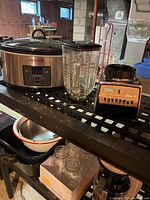 Slow cooker, blender base, glass jar and lids on shelving