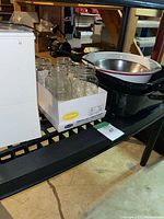 Jars in box, white coffee maker, enamel and stainless bowls on shelf