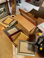 Box containing multiple empty picture frames in assorted finishes and sizes