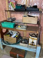 Shelving unit holding drill, lantern, trowels, toolbox, hardware bins and boxed light fixture